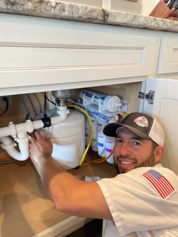 Troy from Wild West Plumbing installing a Kenai water filtration system under a sink in Columbia Falls, MT