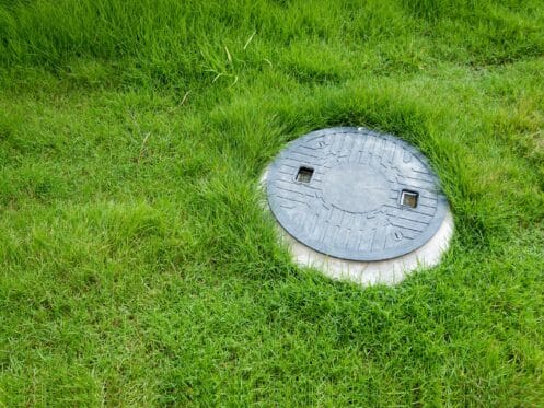 Septic tank access lid set flush in a green lawn